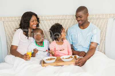 Happy family having breakfast in bed together