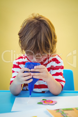 Small boy using a bottle of glue