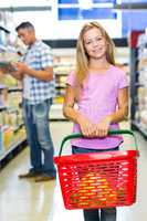 Smiling child holding basket at the supermarket