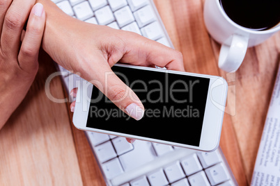 Businesswoman using her smartphone on desk