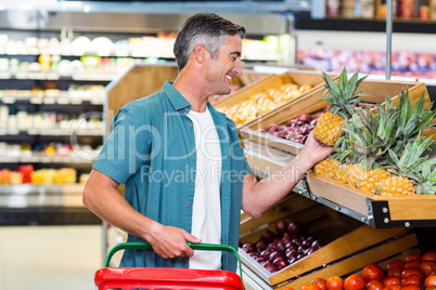 Smiling man choosing pineapple