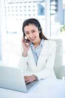 Smiling businesswoman with headset using laptop