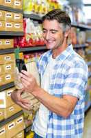 Smiling man with grocery bag using smartphone