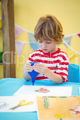 Small boy using a bottle of glue