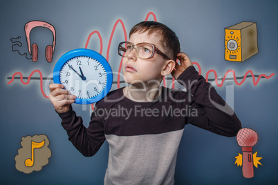 Teenage boy holding a watch and looks up scratching his head a s