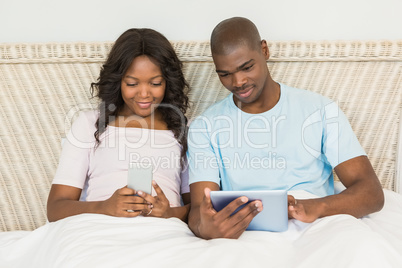 Relaxed couple using technology on bed