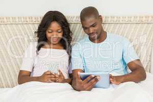 Relaxed couple using technology on bed