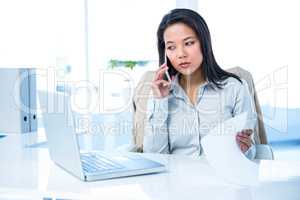 Smiling businesswoman on phone reading document