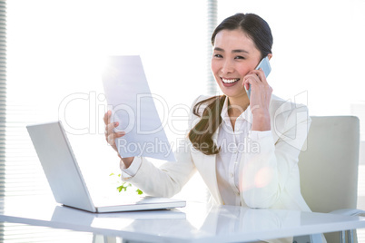 Smiling businesswoman with document phoning