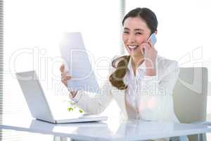 Smiling businesswoman with document phoning