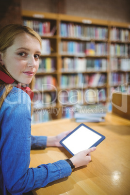 Pretty student with headphones using tablet in library