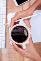 Businesswoman holding coffee cup and pen