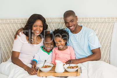 Happy family having breakfast in bed together