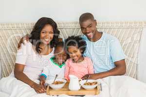 Happy family having breakfast in bed together