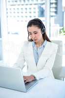 Smiling businesswoman with headset using laptop