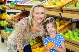 Mother with her daughter buying orange