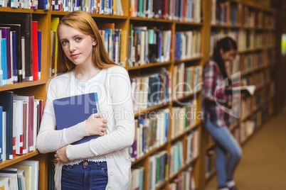 Smiling student leaning against bookshelves