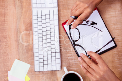 Businesswoman holding pen and eye glasses