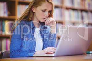 Focused student using laptop in library