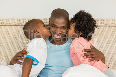 Children kissing father in bed