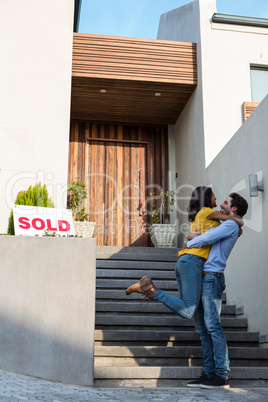 Happy couple hugging in front of new house