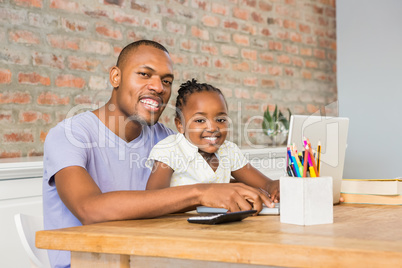 Cute daughter using laptop at desk with father