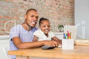 Cute daughter using laptop at desk with father