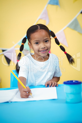Smiling girl drawing in her colouring book