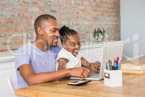 Cute daughter using laptop at desk with father