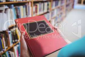 Over shoulder view of student in library holding book