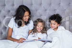 Happy family reading book on the bed