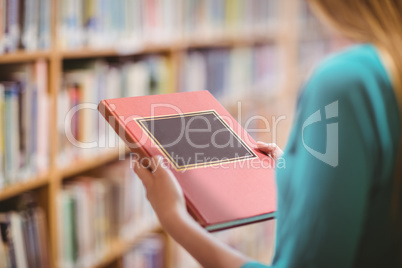 Over shoulder view of student in library holding book