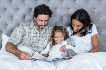 Happy family on bed reading book