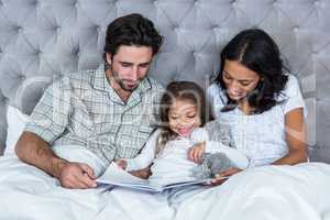 Happy family on bed reading book
