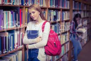 Smiling student leaning against bookshelves