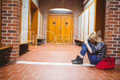 Thoughtful student sitting on the floor against the wall