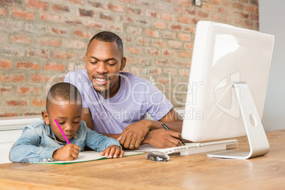 Cute son doing his homework with father