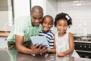 Father using tablet with his children in kitchen