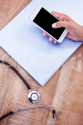 Doctor using smartphone on wooden desk