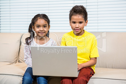 Young smiling siblings using laptop