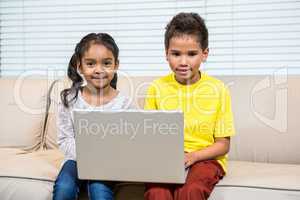 Young smiling siblings using laptop