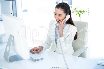 Smiling businesswoman on phone using computer