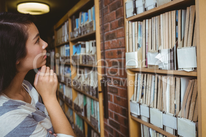 Pretty student looking at bookshelves