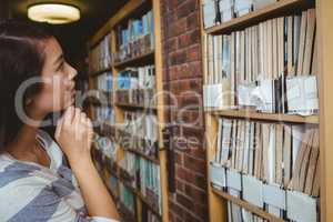 Pretty student looking at bookshelves