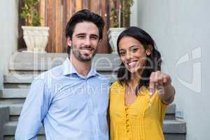 Happy couple in front of new house showing keys