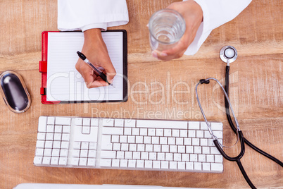 Doctor holding pen and glass of water