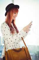 Smiling hipster woman texting with her smartphone