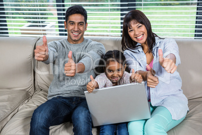 Happy young family using laptop with thumbs up