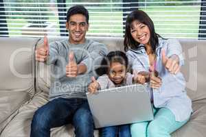 Happy young family using laptop with thumbs up