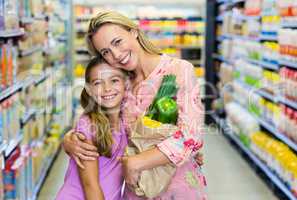 Smiling mother and daughter with grocery bag